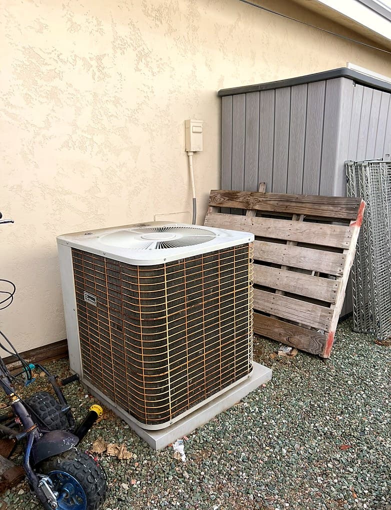 Before: an aging condenser with rusted fins in a side yard